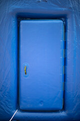 Blue door to portable sauna. Inflatable room. Entrance to building.