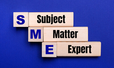 On a bright blue background, light wooden blocks and cubes with the text SME SUBJECT MATTER EXPERT