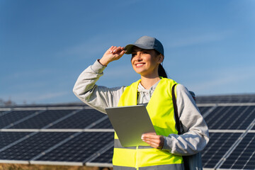 Female energy specialist looking away with happy smile after using digital tablet for reading...