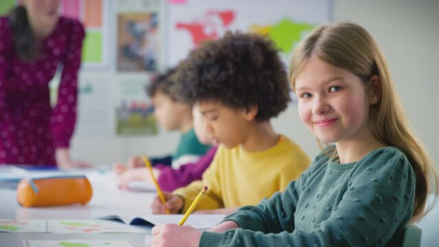 Portrait of female student writing in books during lesson with female teacher in background - shot in slow motion