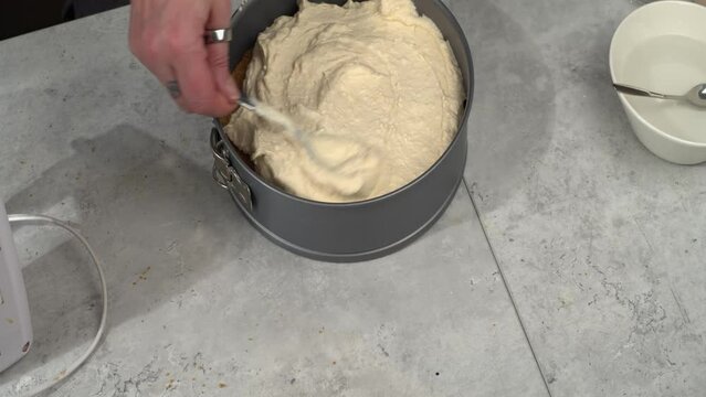 Cheesecake filling smoothed onto crumble crust in springform pan