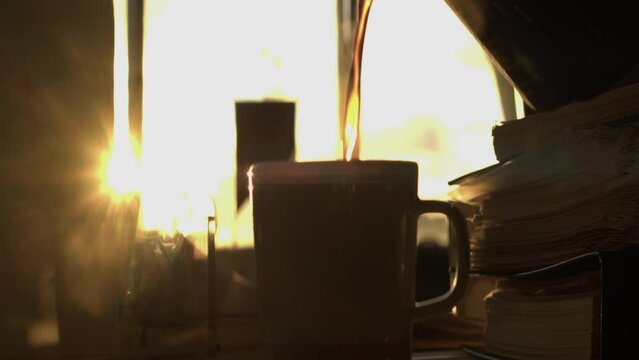 Narrow focus: Backlit coffee poured into mug against sunrise in window
