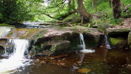 Slow moving peaceful  moorland stream in the Derbyshire Peak District with water flowing over small and large rocks. Shot by low flying drone.