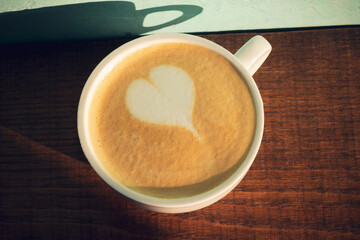 Cup of cappuccino with latte art near green wall