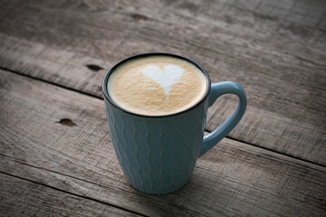 Cappuccino in a blue cup on a wooden surface
