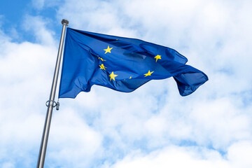 Flag of EU waving in the hard wind against blue sky