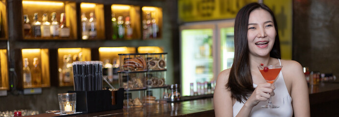 Asian alone women enjoy cocktails in front of a vintage bar, Relaxing activities after work or hangouts, Place of entertainment for young adolescents or night club party.