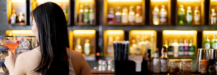 Young Asian woman with a sad face drinking cocktails in front of a vintage bar, Relaxing activities after work or hangouts, Place of entertainment for young adolescents or night club party.