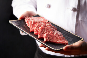 Chef holding fresh raw meat on plate	