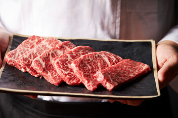 Chef holding fresh raw meat on plate	