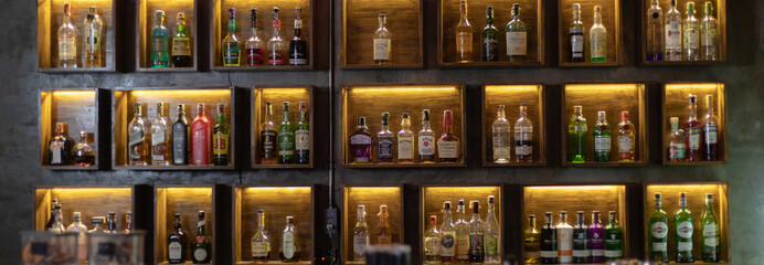 Wide variety of bottles of alcohol or liqueur are placed on the shelves of a vintage bar in Chiangmai, THAILAND: March 4, 2021 - obrazy, fototapety, plakaty