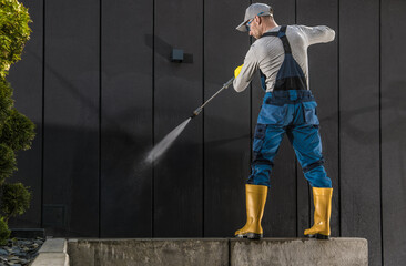 Worker Cleaning Modern Building Dark Wall Using Pressure Washer