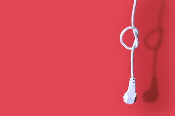 Electric plug for a socket with a knot on a cable on a red background with free space for text. The...