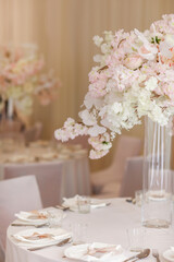 festive wedding decoration. Beautiful fresh white and pink flowers in glass vase on dining table on wedding day. High quality photo