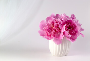 Pink peonies in a vase on a light background. Congratulations on Valentine's Day. Copy space