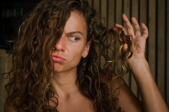 young beautiful curly woman uses care  for hair. The concept of hair care.
