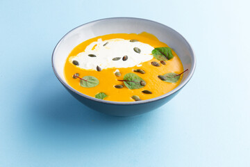 Pumpkin soup in a bowl on a blue background.