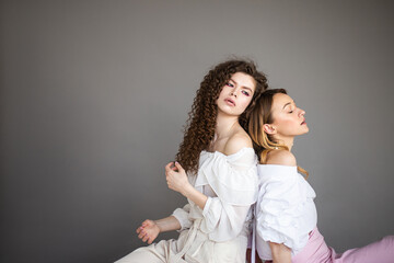 Two fashion female models on a grey background studio portrait of two young stylish girls posing
