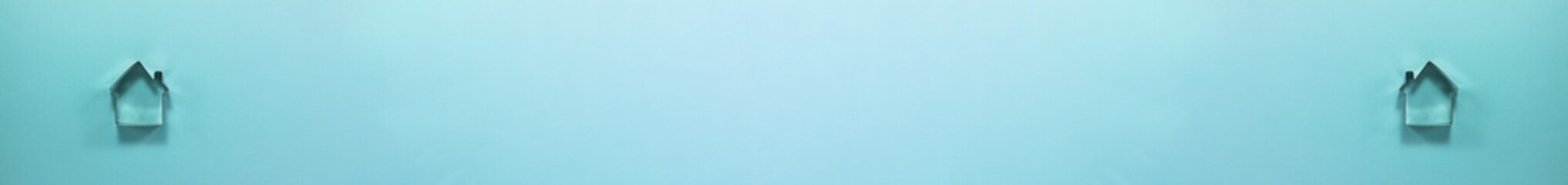 Banner of steel house shaped cutter for cookies from above. Flat lay top view. Confectionery cooking concept with copy space on bright blue paper back