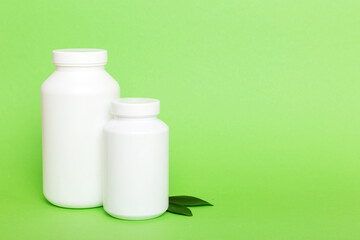 supplement pills with medicine bottle health care and medical top view. Vitamin tablets. Top view mockup bottle for pills and vitamins with green leaves, natural organic bio supplement, copy space