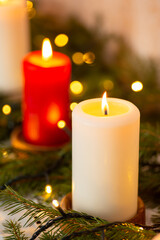 Close-up of burning candles with lights and fir-tree branches on top on table. Christmas decorations