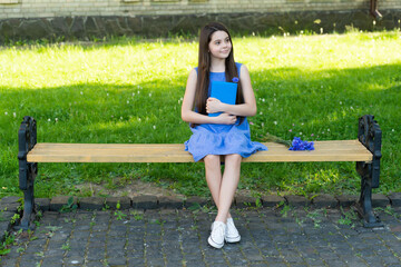 cheerful girl relax with book on park bench, copy space