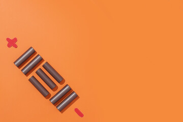 Battery in pattern on orange background. Concept charging, environmental pollution, electrical devices. Flat lay, copyspace