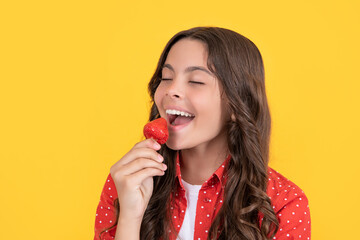 happy teen girl eat strawberry on yellow background