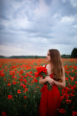 Ukrainian girl stands with a bouquet of poppies in a poppy field