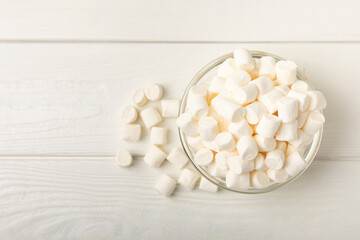 Fototapeta na wymiar Marshmallow in a glass bowl on a white textured background.Closeup chewy candy.Snacks and snacks for parties.Spice for coffee and cocoa.Winter food concept.Place for text.Space for copy.