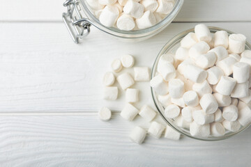 Fototapeta na wymiar Marshmallows in a glass bowl and jar on a white textured table.Sweets and snacks for a snack.Chewy candy close-up.Copy space.Place for text.