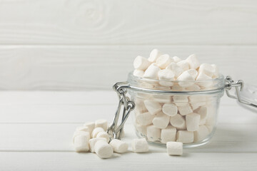 Fototapeta na wymiar Marshmallow in a glass jar on a white wood background. Sweets and snacks for a snack.Copy space.Place for text