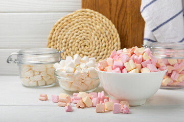 Fototapeta na wymiar Many different marshmallows in bowls and jars on a white textured wood. White and fruit marshmallow. Sweets and snacks for a snack. Chewing candies close-up. Copy space. Place for text.