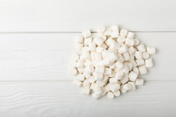 Loose white marshmallows on white texture wood.Sweets and snacks for a snack.Chewy candy close-up.Copy space.Place for text.