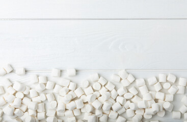 Loose white marshmallows on white texture wood.Sweets and snacks for a snack.Chewy candy close-up.Copy space.Place for text.