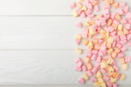 Loose fruit marshmallows on white texture wood.Sweets and snacks for a snack.Chewy candy close-up.Copy space.Place for text.
