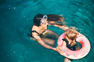 Baby girl swimming with Inflatable ring in the sea. Mother and daughter swimming in the sea.