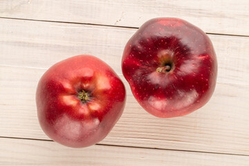 Two ripe red apples on a wooden table, close-up, top view.
