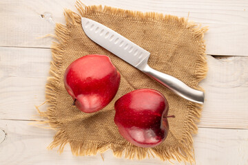 Two ripe red apples with a knife on a jute napkin, close-up, top view.