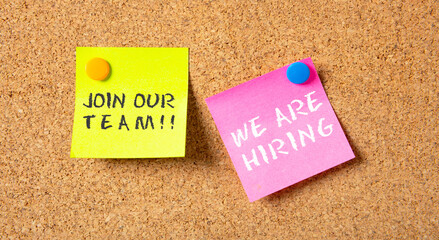We Are Hiring in pink post it, Join Our Team in yellow one, on bulletin board cork background.