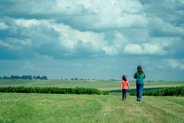 Two young girls sisters walking in the green field.  Childhood, nature, happiness and healthy lifestyle concept. Copy space.