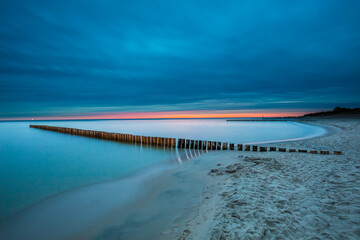 Amazing sunrise over the beach in Chalupy. Seascape with breakwater