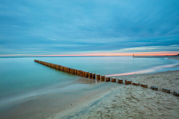 Fototapeta na wymiar Amazing sunrise over the beach in Chalupy. Seascape with breakwater