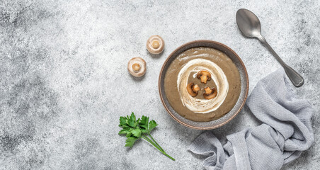 Mushroom cream soup in a bowl on a gray grunge background. Vegetarian organic soup. Healthy food concept. View from above. Banner