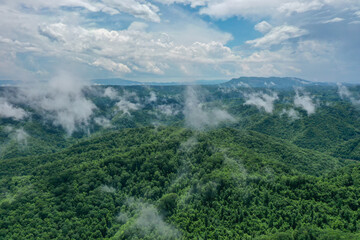 Misty Clouds Over Green Mountains with Blue Sky