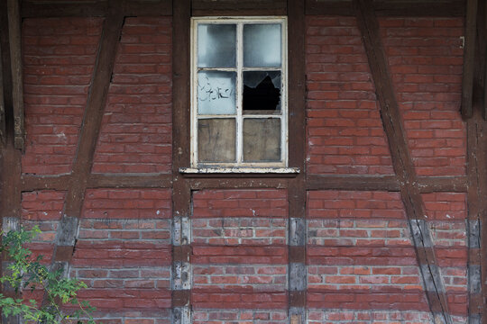 Verfallenes Haus mit kaputtem Fenster und altem Tor