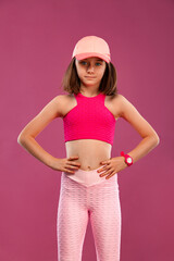 Kid girl doing fitness exercises on pink and pink background in sportswear. Sports concept.