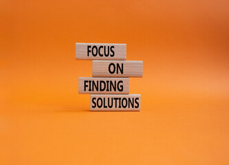 Focus on finding solutions symbol. Concept words Focus on finding solutions on wooden blocks. Beautiful orange background. Business and Focus on finding solutions concept. Copy space