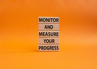 Monitor and Measure your Progress symbol. Wooden blocks with words Monitor and Measure your Progress. Beautiful orange background. Business and Monitor and Measure your Progress Copy space