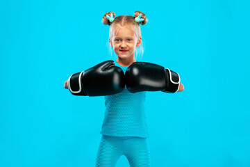 Boxing and fitness concept. Sportsman, girl kid boxer fighting in gloves on blue background.